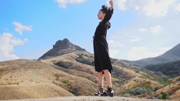 Пригодницька подорож - щаслива молода жінка вигулює на вершині гори і підморгує перед камерою — стокове відео