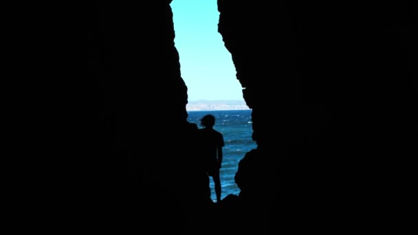 Silueta negra de una pareja recta caminando en una cueva marina — Vídeos de Stock
