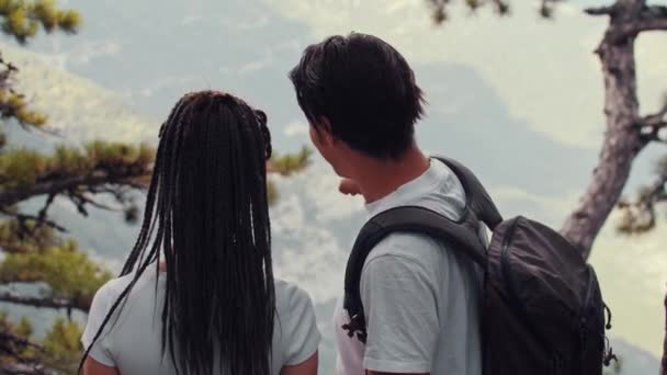 Jovem casal bonito de caminhantes andando na floresta e olhando para as montanhas — Vídeo de Stock