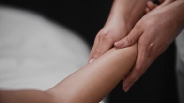 Stüdyoda masaj yaptıran genç bir kadın. Koluna hafif bir masaj yapıyor.