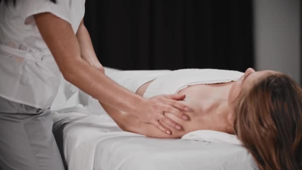 Jonge vrouw met een massage sessie - liggend op de bank terwijl de masseuse werken met haar arm — Stockvideo