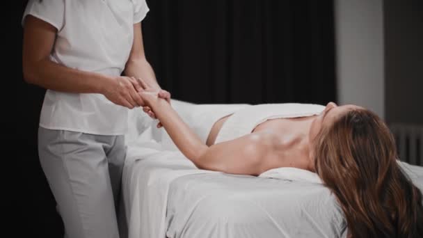 Mladá žena při masáži ve skříni - leží na gauči a masérka si masíruje dlaň — Stock video