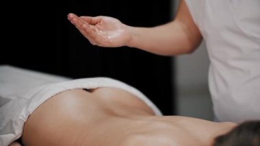 Masaj seansı. Masöz dolabındaki koltukta uzanmış dinlenen kadın vücuduna yağ sürüyor.