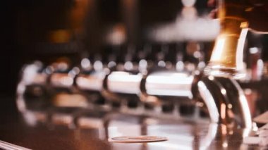 Barmen kürsüye bir bardak bira koyar ve diğer kişi alır.