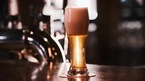 Набросок пива с пеной в стакане на стойке — стоковое видео