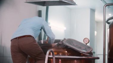 Bira fabrikasında çalışan bir adam büyük bir kürekle teneke kutunun içindekileri karıştırıyor.