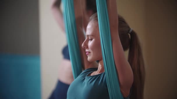 Aerial Yoga - blonde junge Frau sitzt und balanciert in der Yoga-Hängematte — Stockvideo