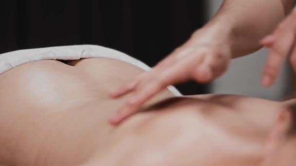 Масажна сесія - масажистка м'яко погладжує шкіру свого клієнта пальцями — стокове відео