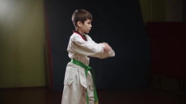 Tekvando yapan küçük bir çocuk - pozisyonda duruyor ve hareketlerini gösteriyor