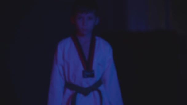 Seorang anak kecil melakukan gerakan taekwondo dalam gelap dengan lampu neon — Stok Video