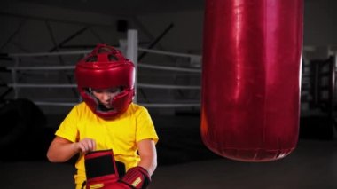 Küçük bir çocuk boks eldiveni giyiyor.