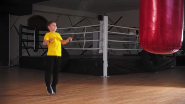 Ein kleiner Junge springt über das Seil in der Nähe des Boxrings — Stockvideo