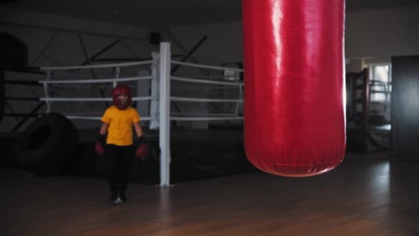 Mały chłopiec bokser idzie do worka treningowego i stoi w pozycji — Wideo stockowe