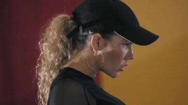 Siyah yarı şeffaf takım elbiseli, dövmeli kadın dansçı sarı stüdyoda seksi danslar yapıyor.