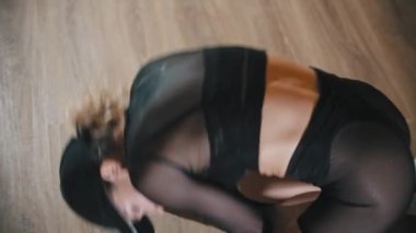 Plastik sarışın kadın yerde striptiz yapıyor.