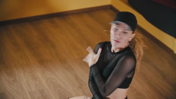 Пластиковая блондинка сексуально танцует на полу в черном полупрозрачном костюме — стоковое видео