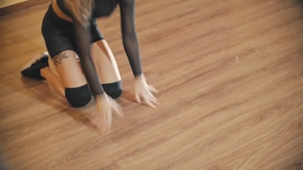 Ξανθιά γυναίκα εκπαιδεύει τον σέξι χορό της στο πάτωμα του στούντιο φορώντας μαύρο διάφανο κοστούμι. — Αρχείο Βίντεο