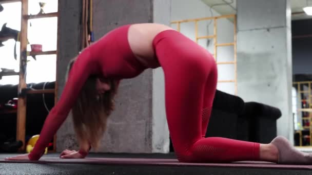 Ung kvinna som gör pilatesövningar för ryggraden i gymmet på yogamattan — Stockvideo