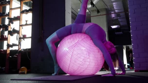 Giovane donna che fa esercizi di pilates esercizio mentre seduto sulla palla fitness in illuminazione al neon — Video Stock