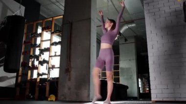 Genç bir kadın spor salonunda ip atlamakla oynuyor.