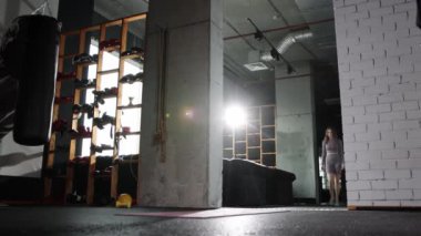 Pilates egzersizi yapan genç bir kadın yoga minderine yürür ve orada durur.