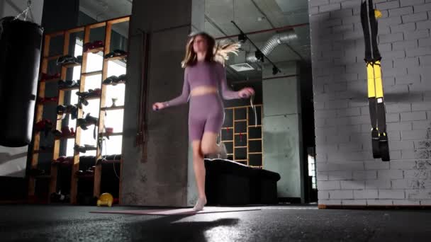 Νεαρή γυναίκα πηδάει πάνω από το σχοινάκι στο γυμναστήριο — Αρχείο Βίντεο