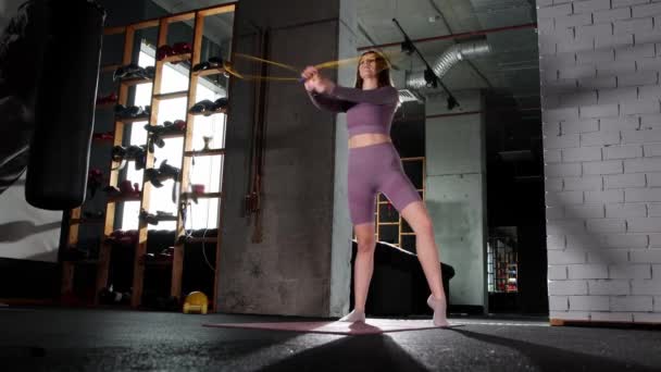 Νεαρή γυναίκα παίζει με ένα σχοινάκι στο γυμναστήριο — Αρχείο Βίντεο