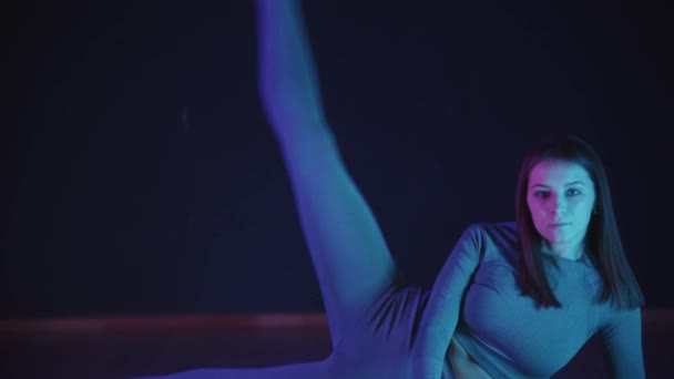 Giovane donna in costume sportivo allungando la gamba e facendo un esercizio di illuminazione al neon — Video Stock