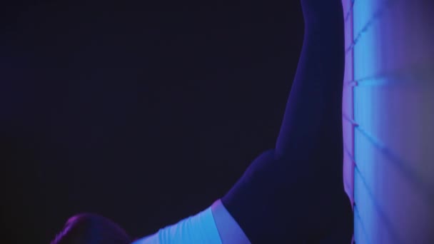Jonge vrouw oefenen in neon verlichting - strekt haar benen tegen de muur — Stockvideo
