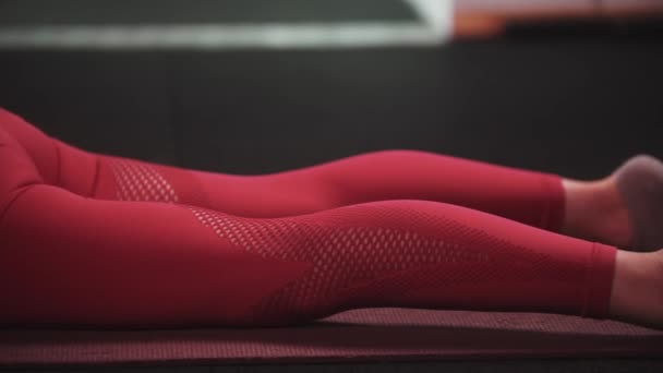 Jonge vrouw in rood sportpak doet fitnessoefeningen in de sportschool - stretching haar rug — Stockvideo