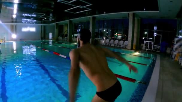 一个留着胡子的年轻人在游泳池里潜水，游到游泳池的底部 — 图库视频影像
