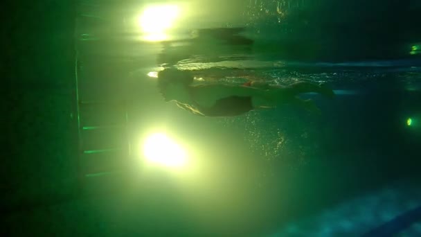 Młoda kobieta pływa pod wodą - odpycha się stopami z boku i zawraca — Wideo stockowe