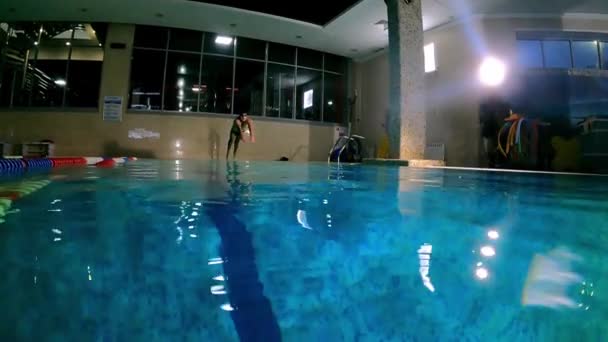 Młody człowiek w basenie nurkuje w wodzie i pływa blisko dna basenu — Wideo stockowe