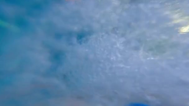 Чоловік у басейні занурюється у воду і плаває, тримаючи камеру — стокове відео