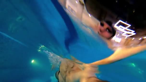 손에 카메라를 들고 물 속에서 수영하고 있는 수염을 기른 젊은 남자 — 비디오