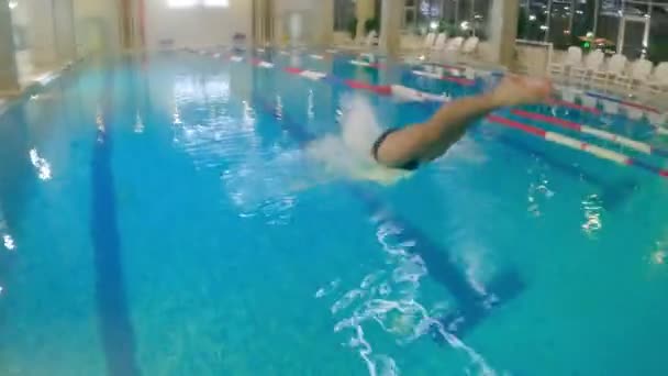 Водные виды спорта - юноша ныряет в воду и начинает плавать под водой — стоковое видео