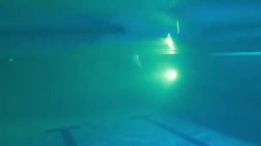 Genç adam arkadan suya atlıyor ve piste doğru gülümsüyor.