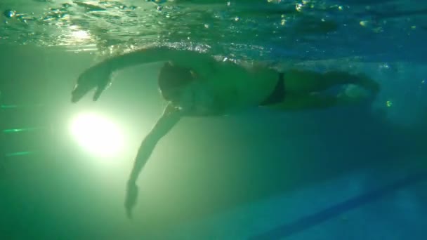 Молодий бородатий чоловік у водонепроникних окулярах плаває під водою відштовхується ногами з боку і повертається назад на колію — стокове відео