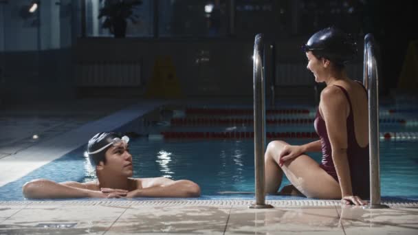 Úszás sport - fiatal férfi és nő úszók beszélnek a medence mellett — Stock videók