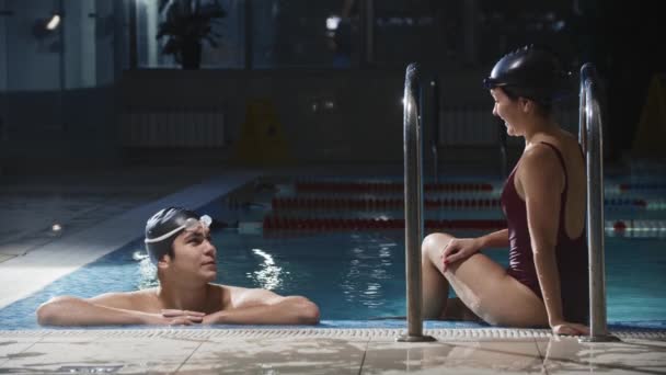 Deportes de natación - hombres y mujeres nadadores jóvenes hablando junto a una piscina y luego continuar el entrenamiento — Vídeo de stock