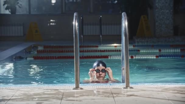 Плавання спорт - молода жінка плаває з басейну на драбині — стокове відео