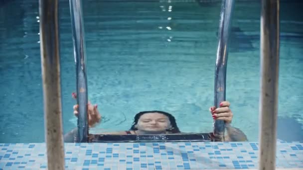 Deportes de natación - nadadora joven sale del agua en la piscina y mira a la cámara — Vídeo de stock