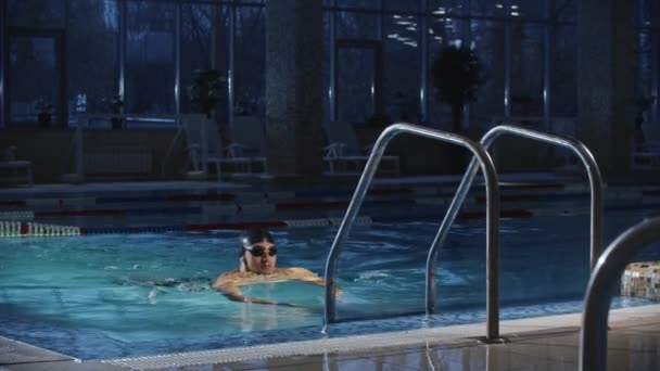 Deportes de natación - joven barbudo usando una escalera en la piscina como soporte para saltar de nuevo al agua — Vídeo de stock