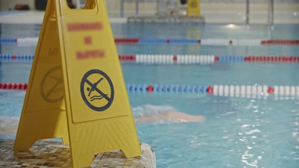 Varovné znamení v blízkosti bazénu - nepotápějte se ve vodě - plavec na pozadí — Stock video