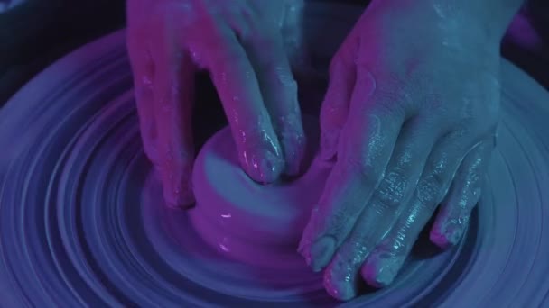 Pottery workshop - hands of young woman makes a recess in the clay - neon lighting — Stock Video