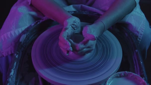 Taller de cerámica - manos femeninas tirando de la arcilla en forma oblonga - iluminación de neón — Vídeos de Stock