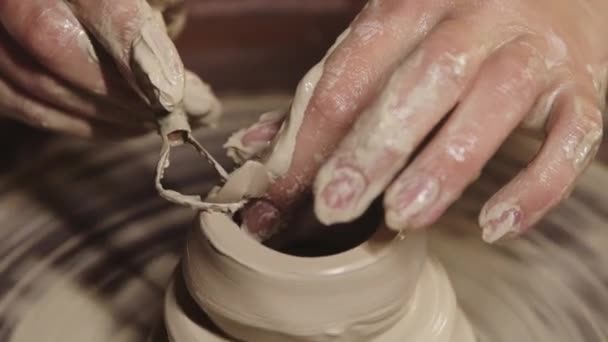 Oficina de cerâmica - mãos femininas molhadas que moldam a argila na roda - cortando a parte superior usando um instrumento — Vídeo de Stock