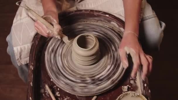 Atelier de poterie - mains féminines façonnant l'argile sur la roue à l'aide d'un outil — Video