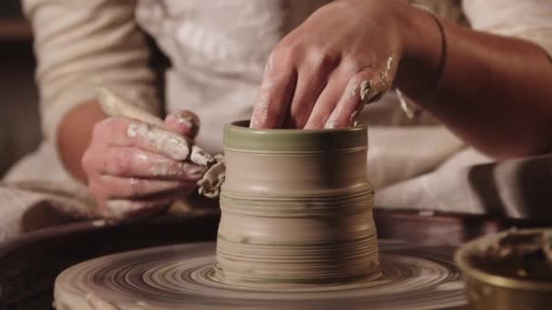 Pottery workshop - female hands making the ribs on the pot shape using a tool — Stock Video
