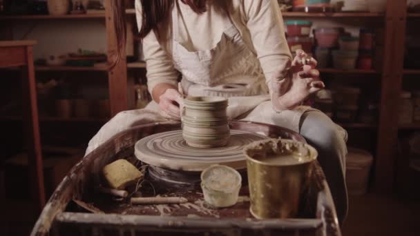 Young woman painting a wet clay pot on a wheel using a brush — Vídeo de Stock